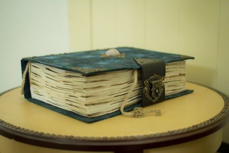 Vintage book with a key on a wooden background in classic blue color, as a concept of historyの写真素材