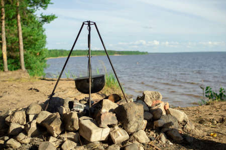 Pot on the fire by the lake. Camping with a pot over a burning fire.の写真素材