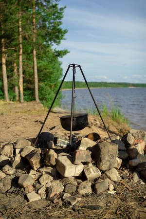 Pot on the fire by the lake. Camping with a pot over a burning fire.の写真素材