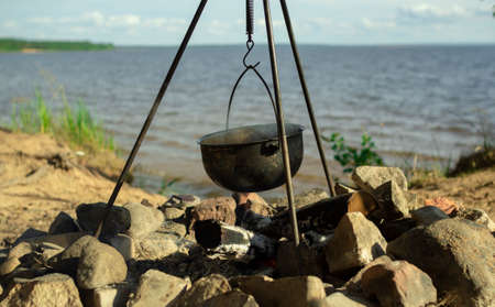 Pot on the fire by the lake. Camping with a pot over a burning fire.の写真素材