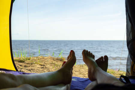 Camping man lying in a tent close-up of his feet . Relaxing on the beach.の写真素材