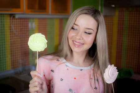 A young woman in pink pajamas holds a sweet dessert in her hands.の写真素材