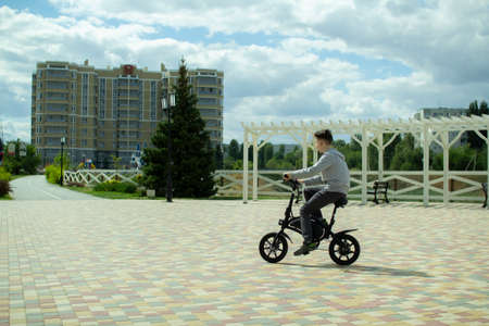 A teenager rides around the city on an electric bike.の写真素材