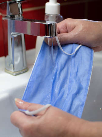 Washing a medical mask in the sink. Cotton reusable medical mask for protection from Covid-19.の写真素材