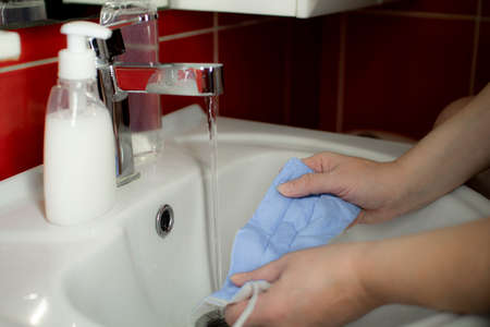 Washing a medical mask in the sink. Cotton reusable medical mask for protection from Covid-19.の写真素材