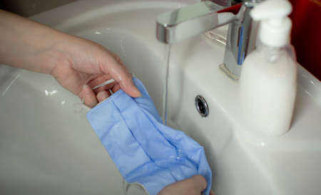 Washing a medical mask in the sink. Cotton reusable medical mask for protection from Covid-19.の写真素材