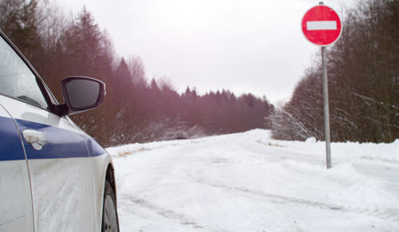 Car in front of a STOP sign on a winter forest road . The safety alert symbol.の写真素材