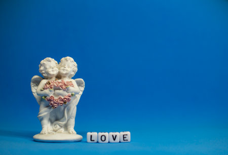 Two cute angels and the word love are made of ivory .Valentines Day. Postcard for the holidays.