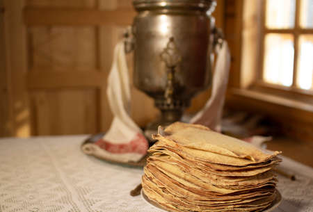 Samovar and pancakes in a wooden house on the background of the window.の写真素材