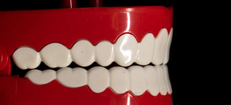 A smiling toy prosthesis, with white teeth and large eyes isolated against a black background.の写真素材