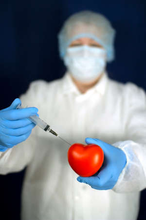The heart and the syringe are in the doctors hands.の写真素材
