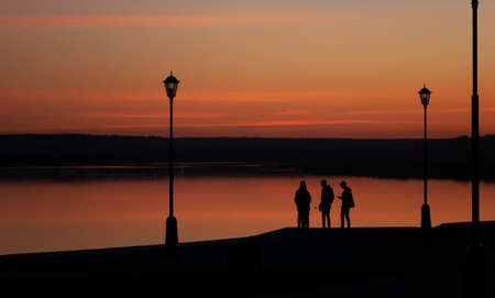 Silhouettes of people on the river embankment.の写真素材