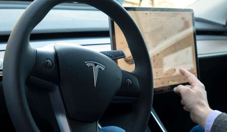 TESLA CAR, RUSSIA, April 2021: A person sitting in an autonomous Tesla car adjusts navigation on the touch console in his autonomous car.のeditorial素材