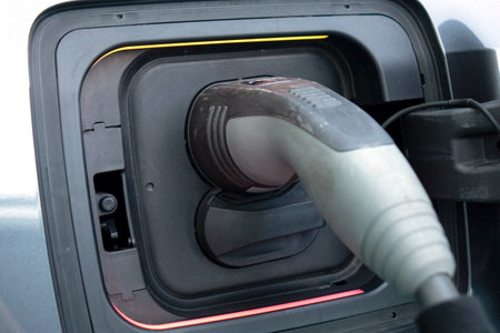 Charging an electric car. Close-up of a power source connected to a charging electrical vehicle.の写真素材