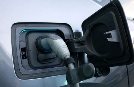 Charging an electric car. Close-up of a power source connected to a charging electrical vehicle.の写真素材