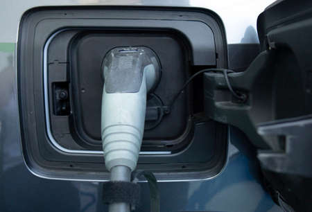 Charging an electric car. Close-up of a power source connected to a charging electrical vehicle.