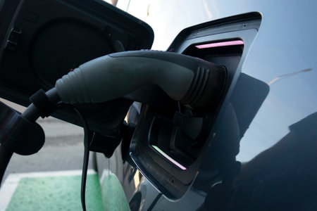 Charging an electric car. Close-up of a power source connected to a charging electrical vehicle.の写真素材