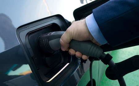 Charging an electric car. Close-up of a power source connected to a charging electrical vehicle.の写真素材