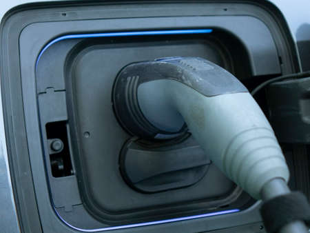 Charging an electric car. Close-up of a power source connected to a charging electrical vehicle.の写真素材