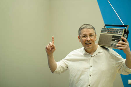 A man with a retro radio on his shoulder stands happy .の写真素材