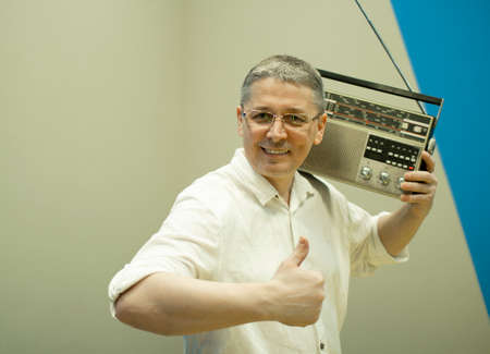 A man with a retro radio on his shoulder stands happy .の写真素材
