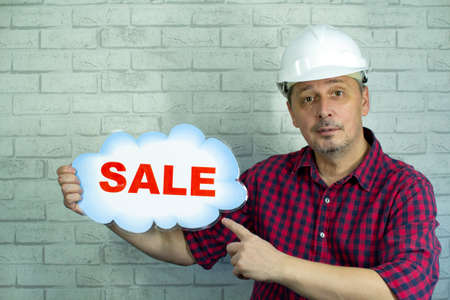 A man in a construction helmet offers a sale.の写真素材