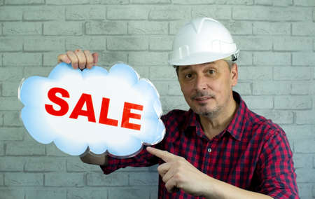 A man in a construction helmet offers a sale.の写真素材