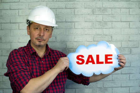 A man in a construction helmet offers a sale.の写真素材