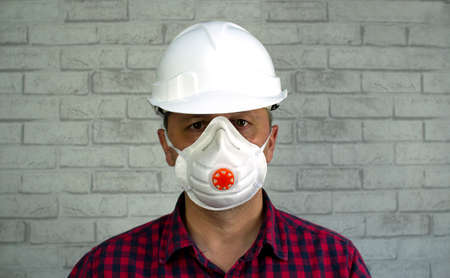 Portrait of a man in a construction helmet and a respirator on his face.の写真素材