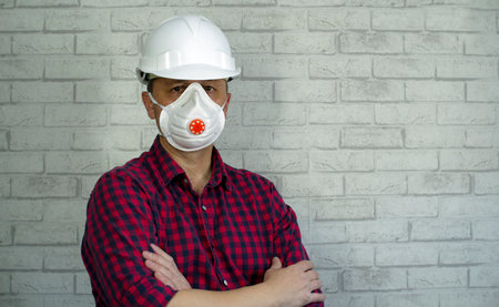 Portrait of a man in a construction helmet and a respirator on his face.の写真素材