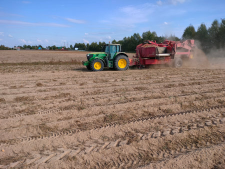 The tractor moves across the field and harvests potatoes. An agricultural machineの写真素材