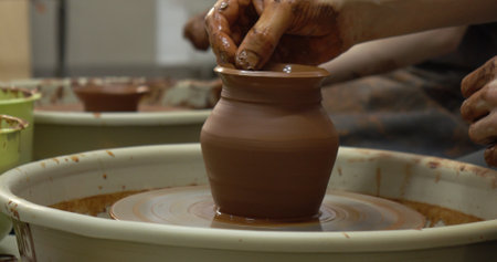 The potters wheel. A close-up of the hands of a craftsman skillfully working with clay on a potters...