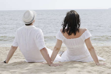Young couple seating on the beachの写真素材