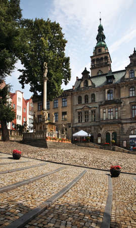 Votive column of Blessed Virgin Mary and townhouse at Market square in Klodzko. Poland