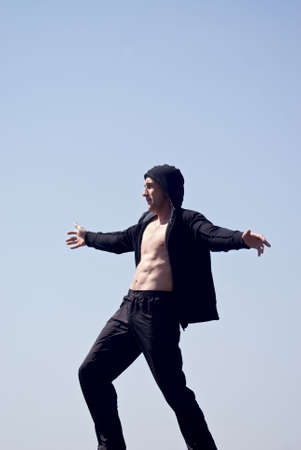 young man with naked chest in the hood with sky backgroundの写真素材