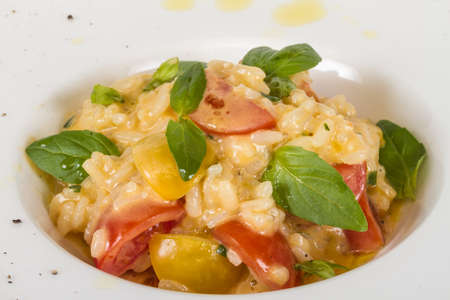 photo of delicious risotto dish with herbs and tomato on white backgroundの写真素材