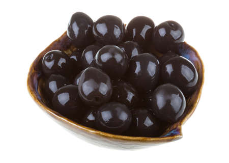 Olives black watered with olive oil in a bowl isolated on a white backgroundの写真素材