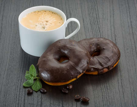 Chocolate donuts with coffee on the deskの写真素材