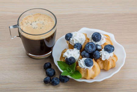 Profiterole with blueberry and cup of coffeeの写真素材
