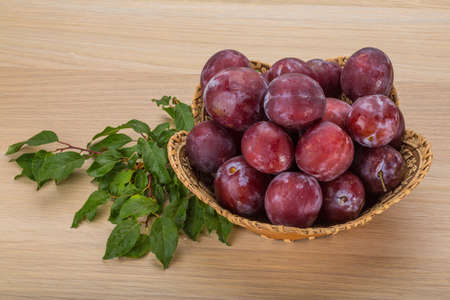 Fresh bright plums in the bowl on boardの写真素材