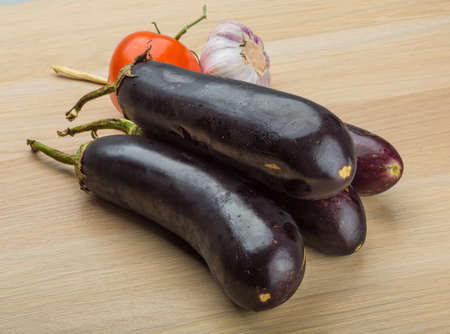 Eggplants on the board with tomato and garlicの写真素材