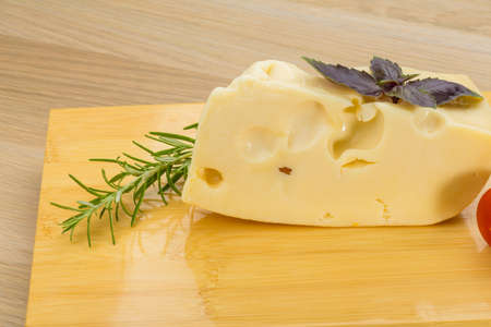 Maasdam cheese on the board with rosemary and mint