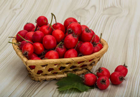 Hawthorn berries in the bowl on wood backgroundの写真素材
