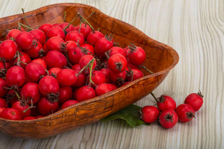 Hawthorn berries in the bowl on wood backgroundの写真素材