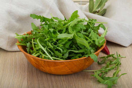 Ruccola leaves mix in the bowl on wooden backgroundの写真素材