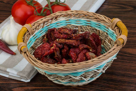 Dried tomtoes in the bowl on wooden backgroundの写真素材
