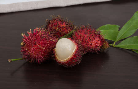 Fresh Rambutan with leaves on the wooden backgroundの写真素材