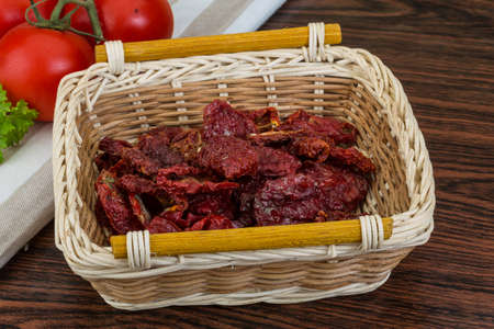 Dried tomtoes in the bowl on wooden backgroundの写真素材