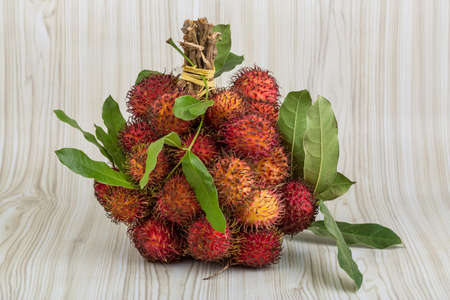 Fresh Rambutan with leaves on the wooden backgroundの写真素材