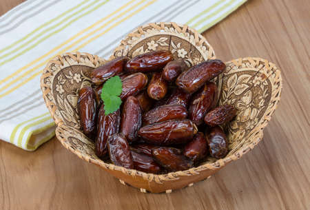 Dry Dates fruit in the bowl on the wood background